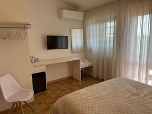 um quarto com uma cama e uma secretária com uma televisão em Villa Lavinia B&B em Montescudaio