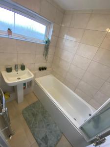 La salle de bains blanche est pourvue d'une baignoire et d'un lavabo. dans l'établissement NEC/Airport/HS2/Resorts World, à Marston Green