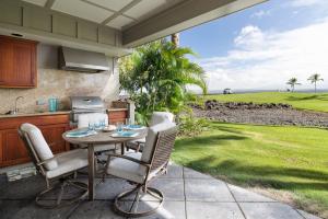 een patio met een tafel en stoelen en een gazon bij Hilton Pool Pass Included - Luxury Living on the Green w Pool Hot Tub & Views in Waikoloa