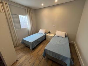 two beds in a small room with a window at Casa Nova - Excelente Localização in Piracicaba