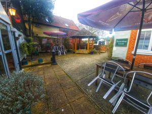 an outdoor patio with chairs and tables and an umbrella at The George & Dragon Hotel in Long Melford