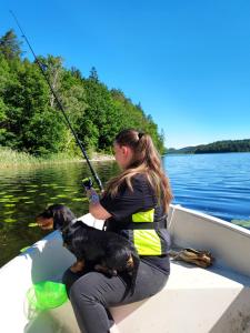a woman in a boat with a dog and a fishing pole at Älgbergets Bed & Breakfast in Ucklum