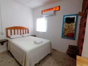 a bedroom with a white bed and a window at Casa Tortuga Azul in Palenque