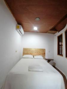 a white bed in a room with a wooden ceiling at Casa Tortuga Azul in Palenque
