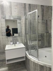 un hombre tomando una foto de un baño con lavabo y ducha en Stay In Carlazo - Unlimited WiFi, Solar backup, en Roodepoort