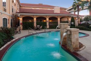 a swimming pool with a water fountain in front of a house at TownePlace Suites by Marriott San Antonio Airport in San Antonio
