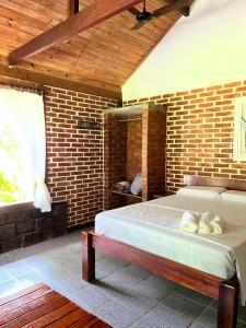 um quarto com uma cama numa parede de tijolos em Sitio Serenar Chalés Equipados em Penedo