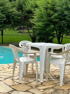 a white table and chairs next to a pool at Sitio Serenar Chalés Equipados in Penedo +19 photos