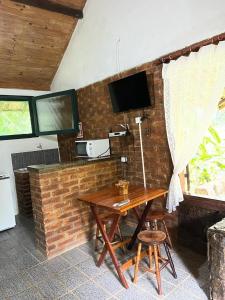 um quarto com uma mesa de madeira e uma televisão numa parede de tijolos em Sitio Serenar Chalés Equipados em Penedo