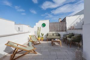 a patio with chairs and furniture on a white wall at Casa Antica Pietra Ostuni in Ostuni