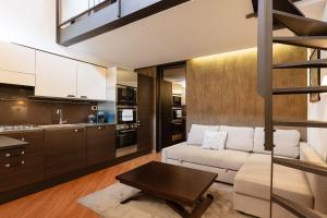 ein Wohnzimmer mit einem weißen Sofa und einer Küche in der Unterkunft Casa del Borgo - Esclusiva Suite centro Monza con vista Duomo in Monza