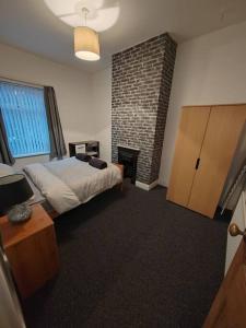 a bedroom with a bed and a brick fireplace at Church View house,2bed,brighouse central location in Brighouse