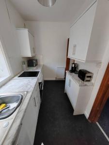 a small kitchen with white cabinets and a sink at Church View house,2bed,brighouse central location in Brighouse