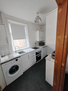 a kitchen with a sink and a washing machine at Church View house,2bed,brighouse central location in Brighouse