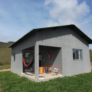 une petite maison avec une terrasse et des chaises. dans l'établissement Chalés Recanto da Baleia, à Alto Paraíso de Goiás