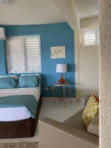 Schlafzimmer mit blauen Wänden, einem Bett und einem Tisch in der Unterkunft Del Marie Studio Apt in Saint Philip