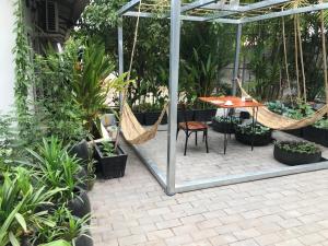 a patio with a table and hammocks and plants at Siem Reap Homesteading in Siem Reap