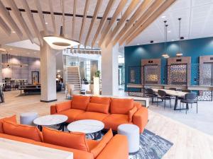 a lobby with a couch and tables and chairs at Novotel Liverpool Paddington Village in Liverpool