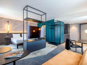 リバプールにあるNovotel Liverpool Paddington Villageのベッドと大型テレビが備わるホテルルームです。