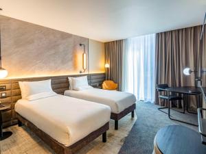 a hotel room with two beds and a table at Novotel Liverpool Paddington Village in Liverpool