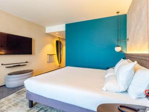 a hotel room with a large white bed and a blue wall at Novotel Liverpool Paddington Village in Liverpool