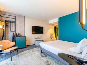 a hotel room with a large bed and a blue wall at Novotel Liverpool Paddington Village in Liverpool