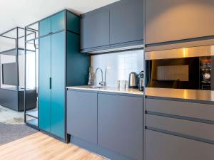 a kitchen with blue cabinets and a microwave at Novotel Liverpool Paddington Village in Liverpool
