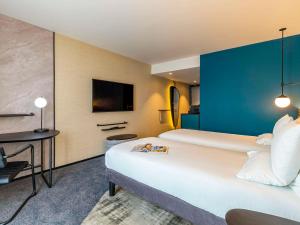 a hotel room with a large white bed and a blue wall at Novotel Liverpool Paddington Village in Liverpool