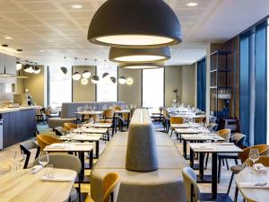 a restaurant with tables and chairs and a large light fixture at Novotel Liverpool Paddington Village in Liverpool