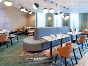 a restaurant with tables and chairs and a couch at Novotel Liverpool Paddington Village in Liverpool