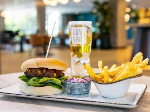 a plate with a hamburger and french fries and a drink at Novotel Liverpool Paddington Village in Liverpool