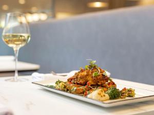 a plate of food on a table with a glass of wine at Novotel Liverpool Paddington Village in Liverpool