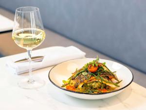 a plate of food and a glass of wine on a table at Novotel Liverpool Paddington Village in Liverpool