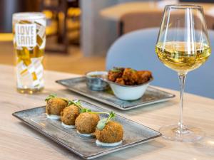 a table with two plates of food and a glass of wine at Novotel Liverpool Paddington Village in Liverpool