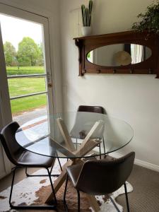 a glass table and chairs in a room with a window at Glenie Cottage BnB Guesthouse in Timaru