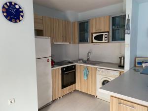 a kitchen with wooden cabinets and a white refrigerator at Blue Lagoon apartment next to the centre Kranevo. in Kranevo
