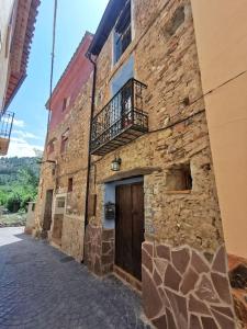 ein Steingebäude mit einer Tür und einem Balkon in der Unterkunft Casa Roya in Montalbán
