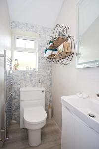 a bathroom with a toilet and a sink and a window at The Bearded Goat Den - A rural retreat at this modern holiday cottage in Saint Leonards