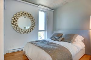 1 dormitorio con 1 cama con espejo en la pared en Les Immeubles Charlevoix - Le 760805, en Quebec