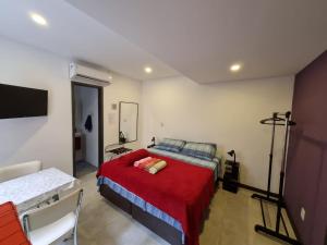 Suítes/Studios Privados Copacabana في ريو دي جانيرو: غرفة نوم بسرير وبطانية حمراء