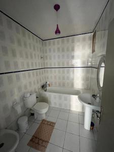 een badkamer met een toilet, een bad en een wastafel bij Appartement City Jardin - Pied sur mer in Martil