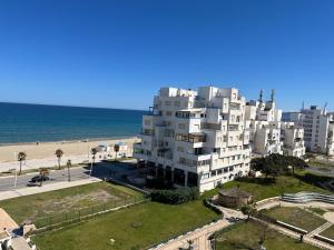een groot wit gebouw naast het strand bij Appartement City Jardin - Pied sur mer in Martil