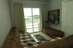 a living room with a couch and a large window at Valentina 24 HORAS in Florianópolis