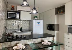 a kitchen with a black counter top and a microwave at Flat 402 Laguna Beach - tipo Loft encantador, mobiliado e aconchegante in Porto De Galinhas