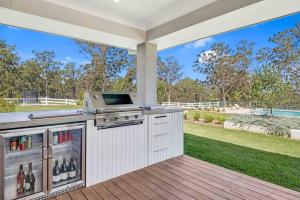 an outdoor kitchen with a grill and a yard at Luxury Hunter Valley Estate in Lochinvar
