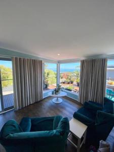 un soggiorno con 2 divani blu e ampie finestre di Salty Paws Dog Friendly Luxe Cottage a San Remo