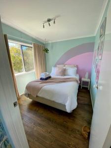 a bedroom with a bed with a purple headboard at Salty Paws Dog Friendly Luxe Cottage in San Remo