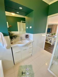 baño con lavabo y pared verde en Salty Paws Dog Friendly Luxe Cottage, en San Remo