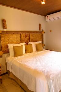 sypialnia z dużym białym łóżkiem z poduszkami w obiekcie Casa do Imperador w mieście Fernando de Noronha
