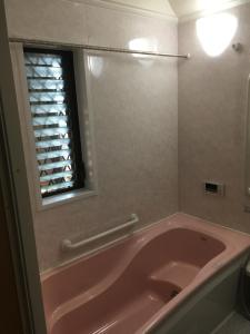 eine rosa Badewanne im Bad mit Fenster in der Unterkunft SUMIDA in Osaka